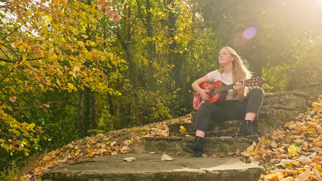 el otoño las hojas doradas caen la chica rubia toca la guitarra el rayo de luz del sol