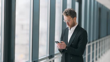 Hombre-De-Negocios-Con-Teléfono-Inteligente-En-El-Corredor-Del-Centro-De-Negocios