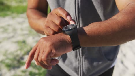 hombre afroamericano de alto nivel haciendo ejercicio usando un reloj inteligente escuchando música