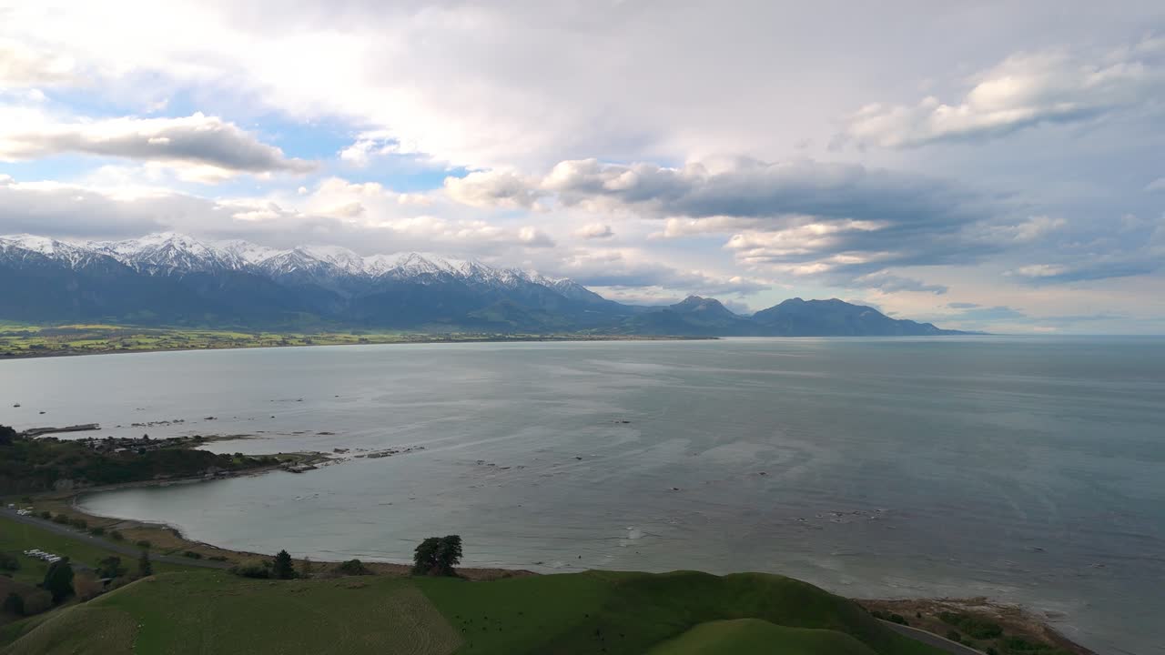 Aerial establishing drone fly at mountain lake in Kaikōura Coastline with Southern Alps Rising Behind, New Zealand