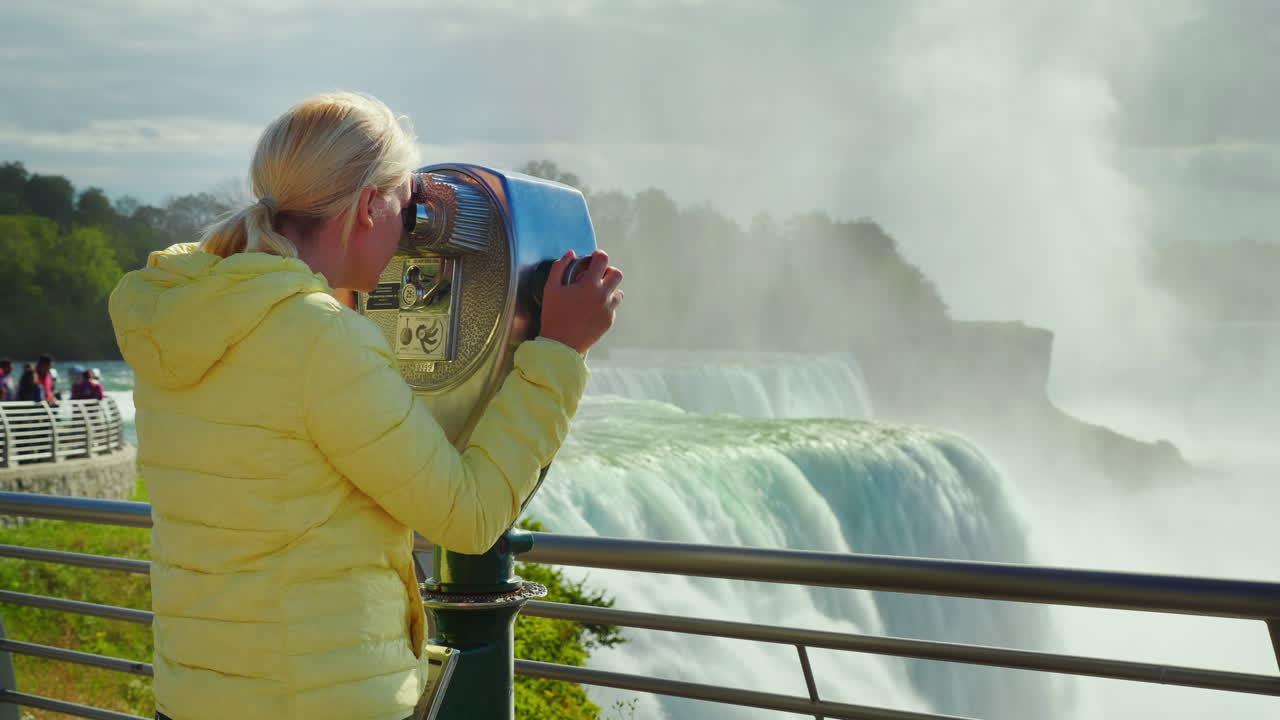 쌍안경으로 나이아가라 폭포를 바라보는 관광객