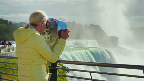 turista mira las cataratas del niágara a través de binoculares
