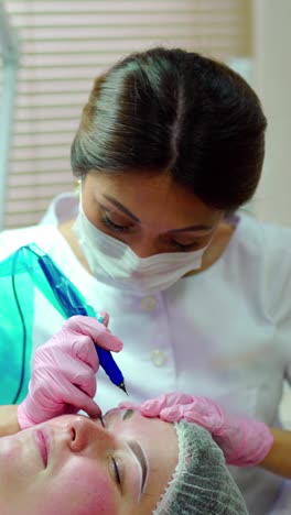 cosmetologist applying permanent make up on eyebrows