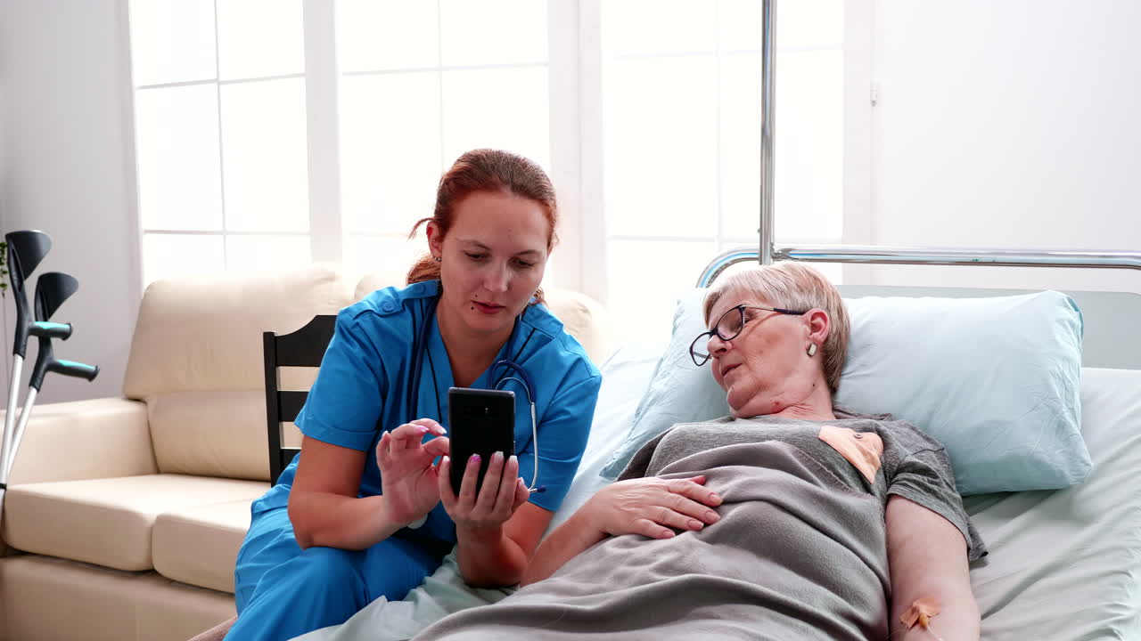 Female nurse helping old woman to use smartphone