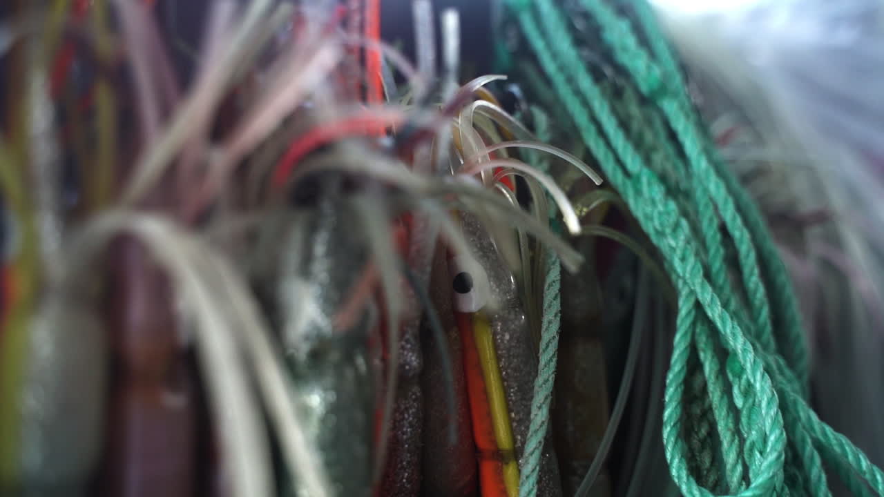 señuelos de pesca colgando al lado de la cuerda en el borde de un barco de pesca de ocio