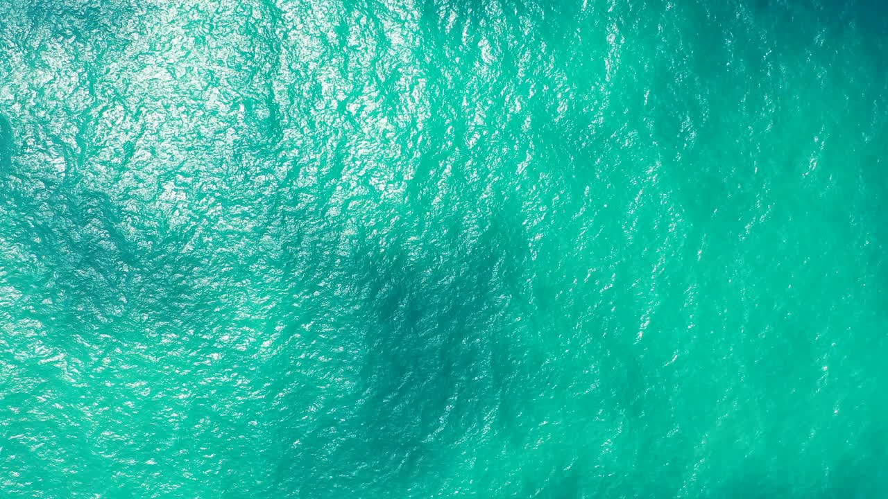 Abstract sea water texture. Beautiful turquoise crystal clear ocean with shade from the clouds. Bahamas