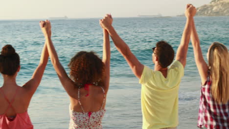 Fünf-Freunde-Stehen-Hand-In-Hand-Am-Strand