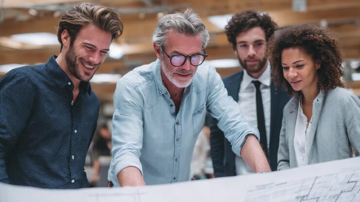 Un team collaborativo impegnato nella pianificazione strategica, che analizza schemi architettonici e idee con entusiasmo e intuizione in un'atmosfera di lavoro moderna.