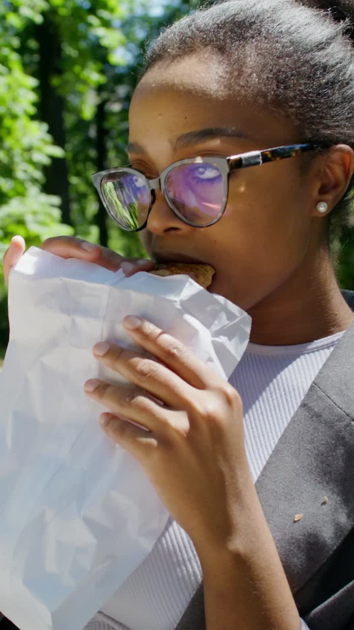 una mujer comiendo un sándwich en un parque.