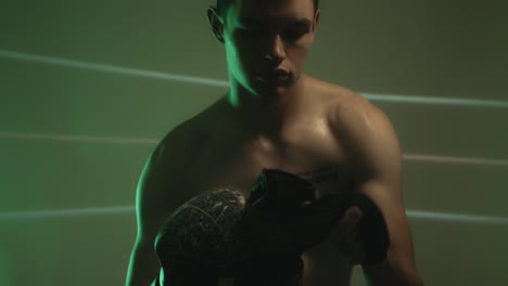 muscular man putting on boxing gloves. medium shot