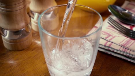 Mineral-water-pouring-into-a-glass,-the-morning-Breakfast,-Slow-motion-with-rotation-tracking-shot.