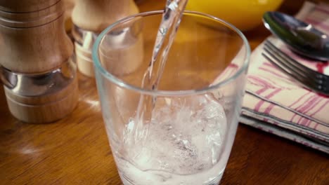 agua mineral vertiendo en un vaso, el desayuno de la mañana, cámara lenta con toma de seguimiento de rotación.