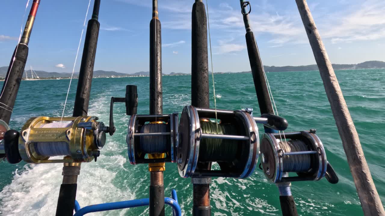 Fishing rods on a boat navigate vibrant turquoise waters under clear skies near Rawai Beach, capturing the essence of a tropical adventure