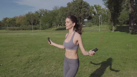 hermosa joven sonriente saltando la cuerda en la naturaleza