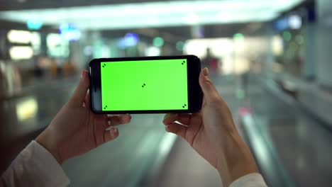 4k, primer plano de una mujer muestra un teléfono de pantalla verde en movimiento en la acera