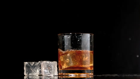 cubos de hielo cayendo en un vaso de whisky y hielo