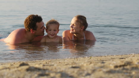 laughing little boy with his parents at the sea