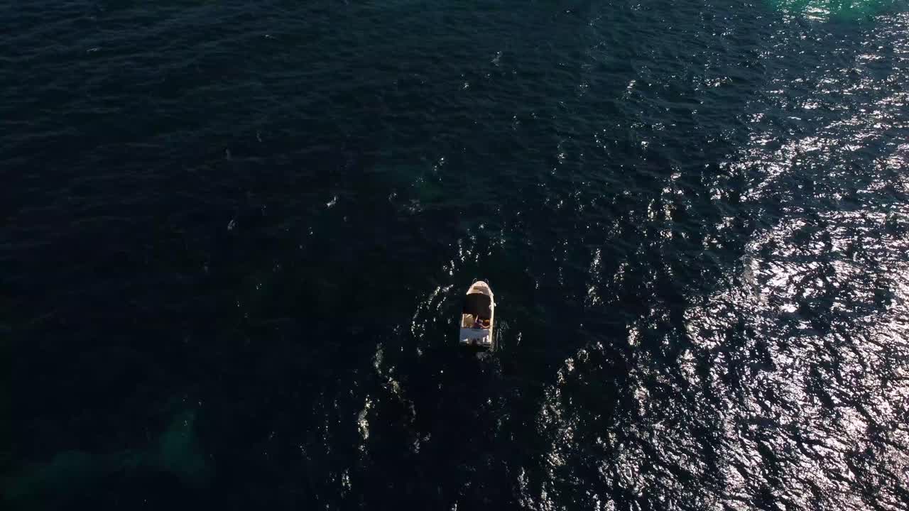 4K aerial arc shot of a small stationary boat in the Balearic Sea, with a gradual rise