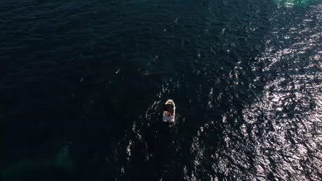 4K-aerial-arc-shot-of-a-small-stationary-boat-in-the-Balearic-Sea,-with-a-gradual-rise