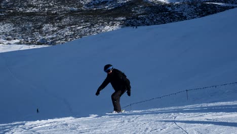person skiing/snowboarding down a snowy mountain slope