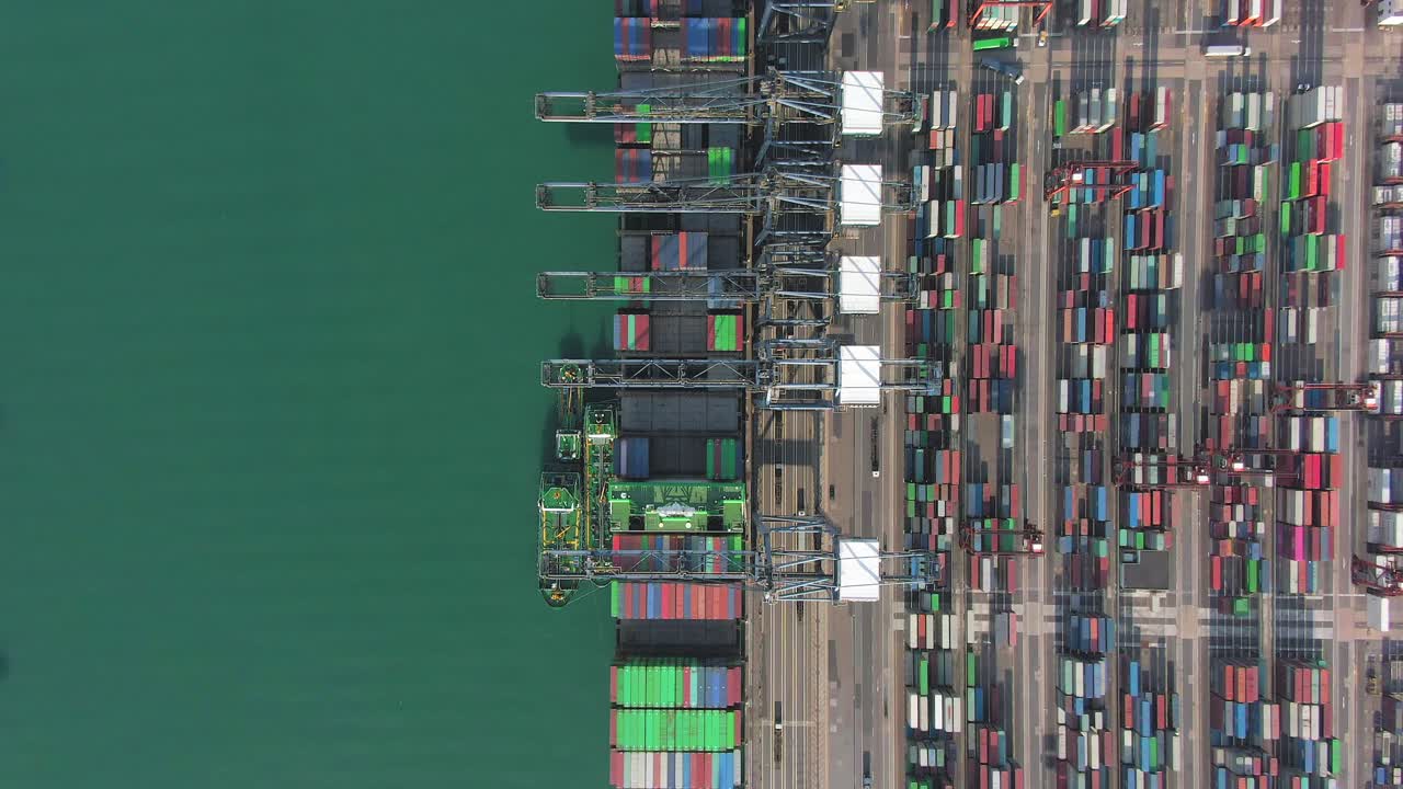 Large Container Ship docked at Hong Kong commercial port, top down aerial view including Stacks of Shipping containers on a holding platform