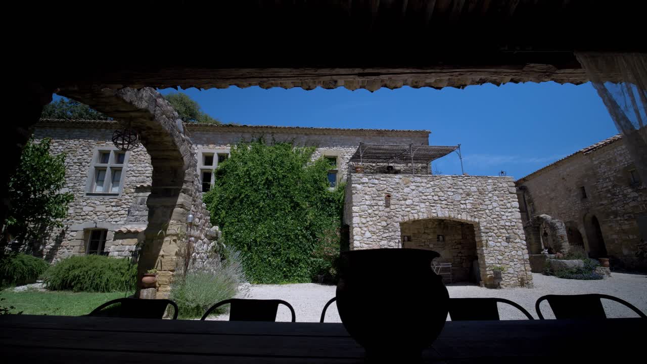 테라코타 지붕, 아치 된 창문, 나무 테이블 이 있는 마당 이 있는 돌집