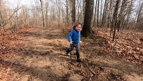 cheerful child running in the forest - bare trees in the autumn forest in crosswinds marsh county park, southeast michigan - wide shot, slow motion