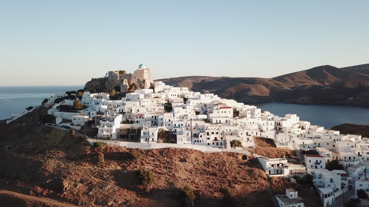 Castle of Astypalea,4K aerial footage of Querini Castle during golden hour. Drone Footage starts from bottom up and than zooms in where only one blue dome of the church is visible over white houses.