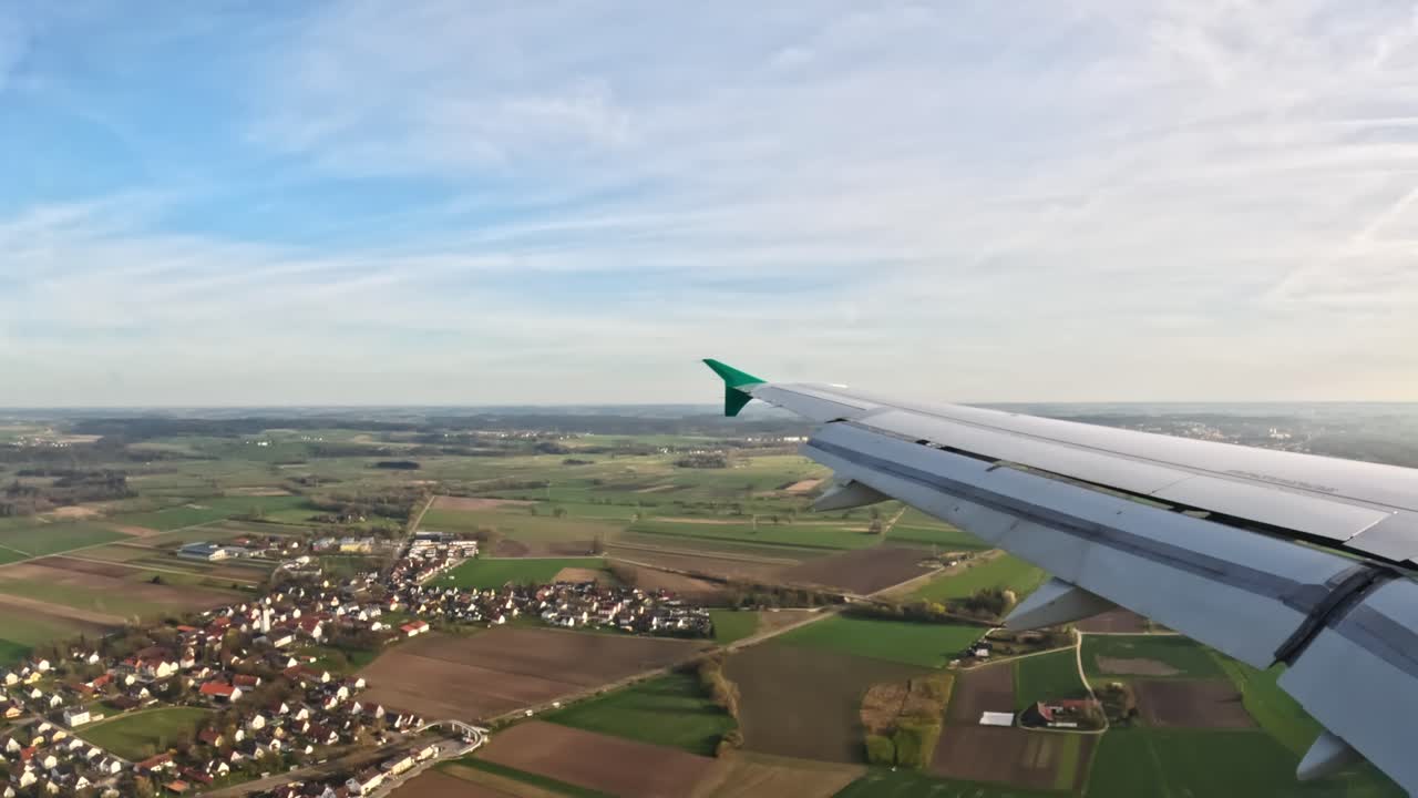 View of green countryside and village through plane window
