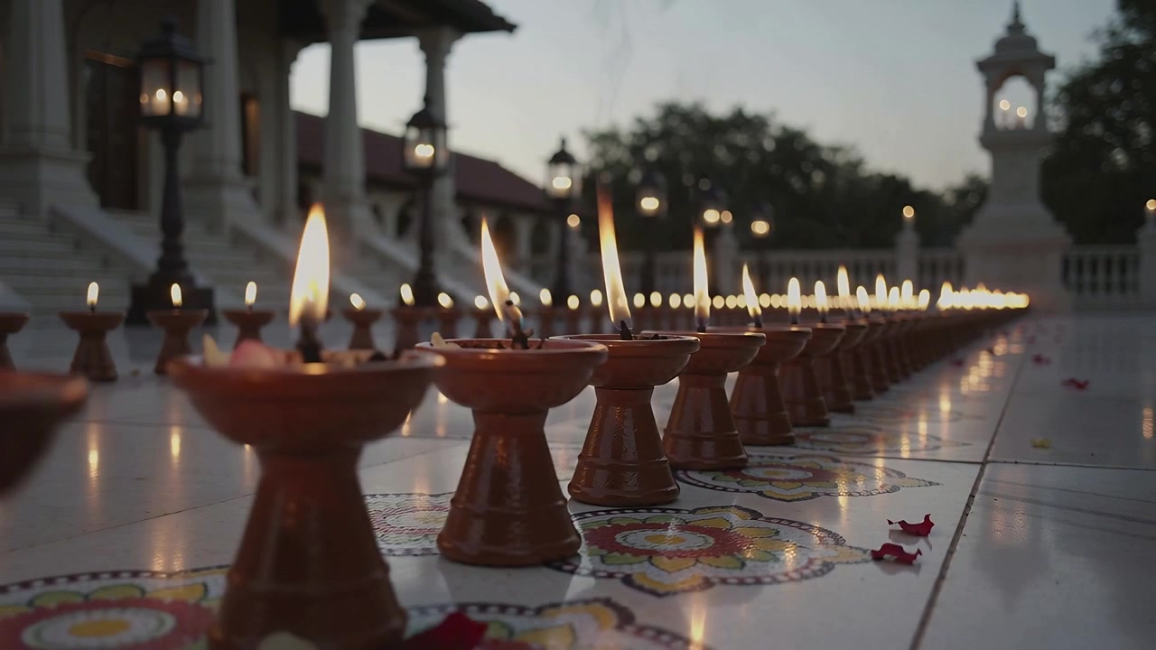 Sliding camera revealing row of clay oil lamps on temple courtyard tiles, marking dusk ritual