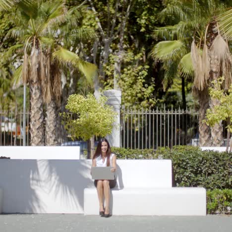 business woman sitting on bench with computer