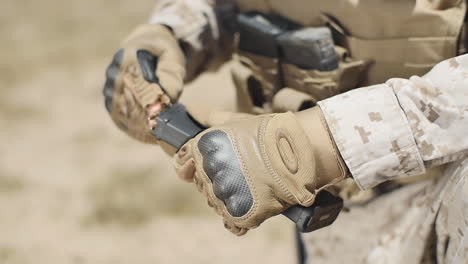 slow motion: a us marine positioned in the desert loads bullets in his assault rifle's clip