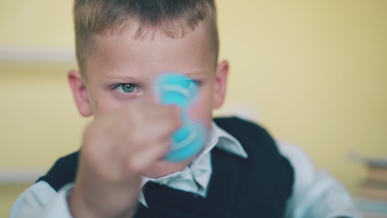 작은 소년 은 교실 에서 휴식 할 때 돌리는 장난감 으로 놀고 있다