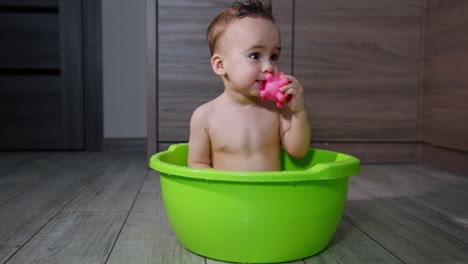 baby bathe in a green plastic bowl