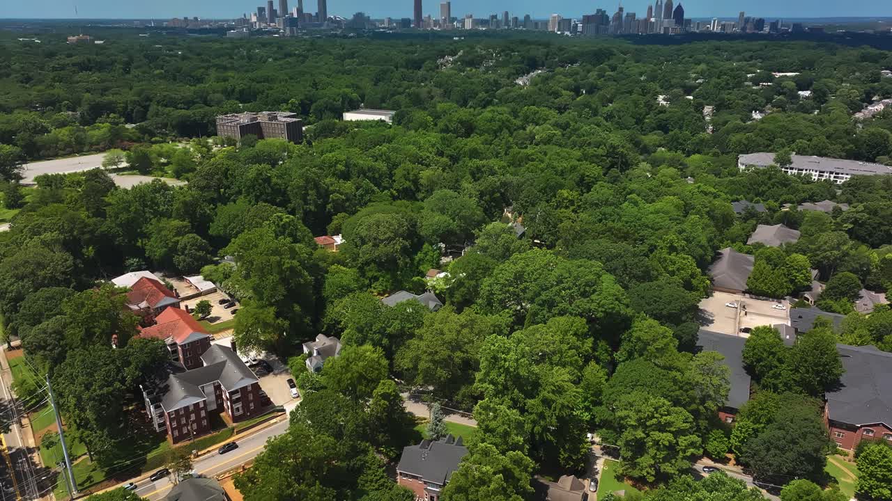Junction in luxury suburb district of Atlanta. Single family houses and one family homes in American town. Green trees in summer. Downtown skyline with skyscrapers in background. Aerial tilt down shot