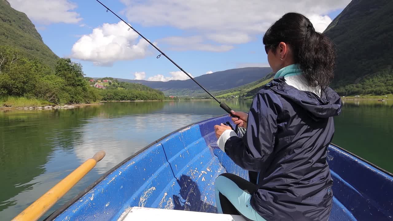 Wanita di perahu menangkap ikan dengan teknik spinning di Norwegia