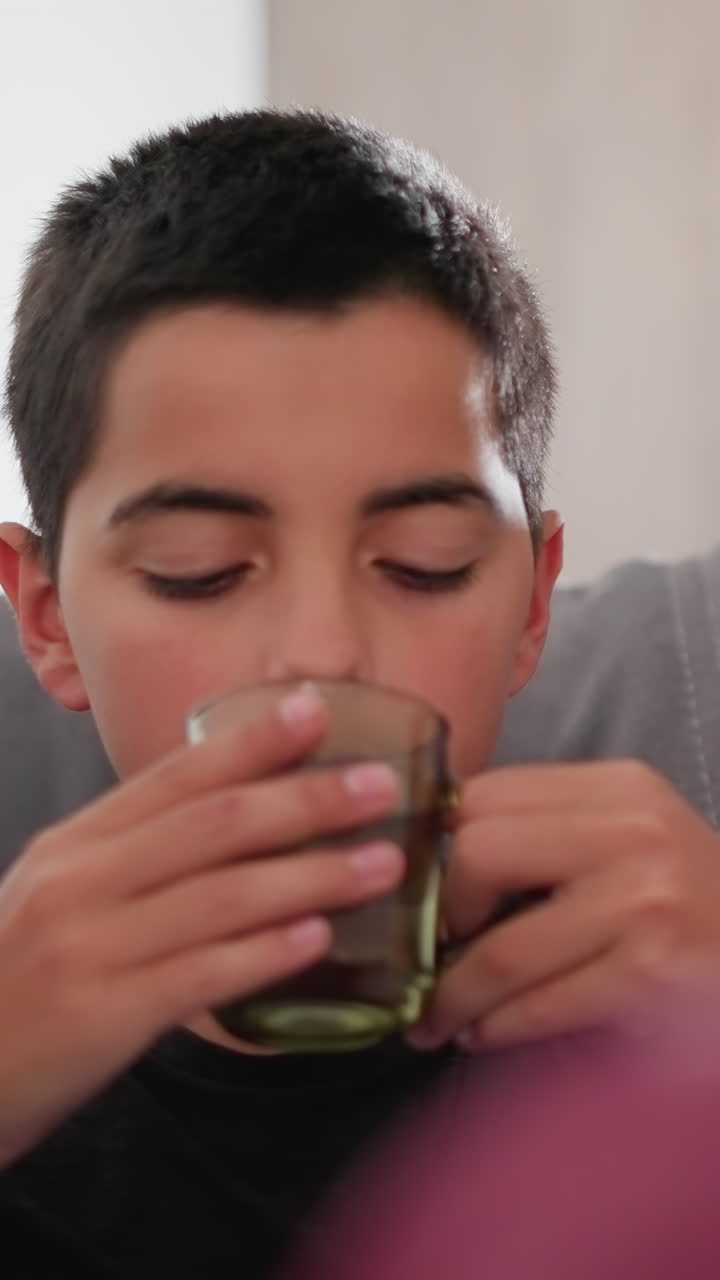 Primer plano de una persona vista de espaldas observando a un niño pequeño tomar su medicación, controlando su salud, gesto de cariño, ayudando con el tratamiento, administrando la medicina, apoyo sanitario