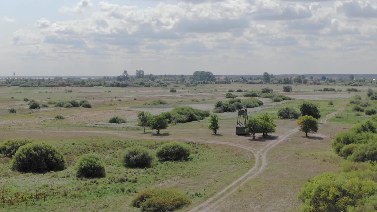 Aerial drone push-out shot of a watchtower in the middle of field in the countryside