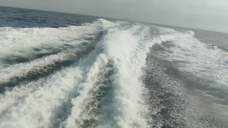 wake of water seen from behind of fast moving motor boat in a clear sky day,blue sea , water surface