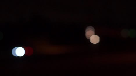 faros de coche fuera de foco, bolas de bokeh en movimiento, noche