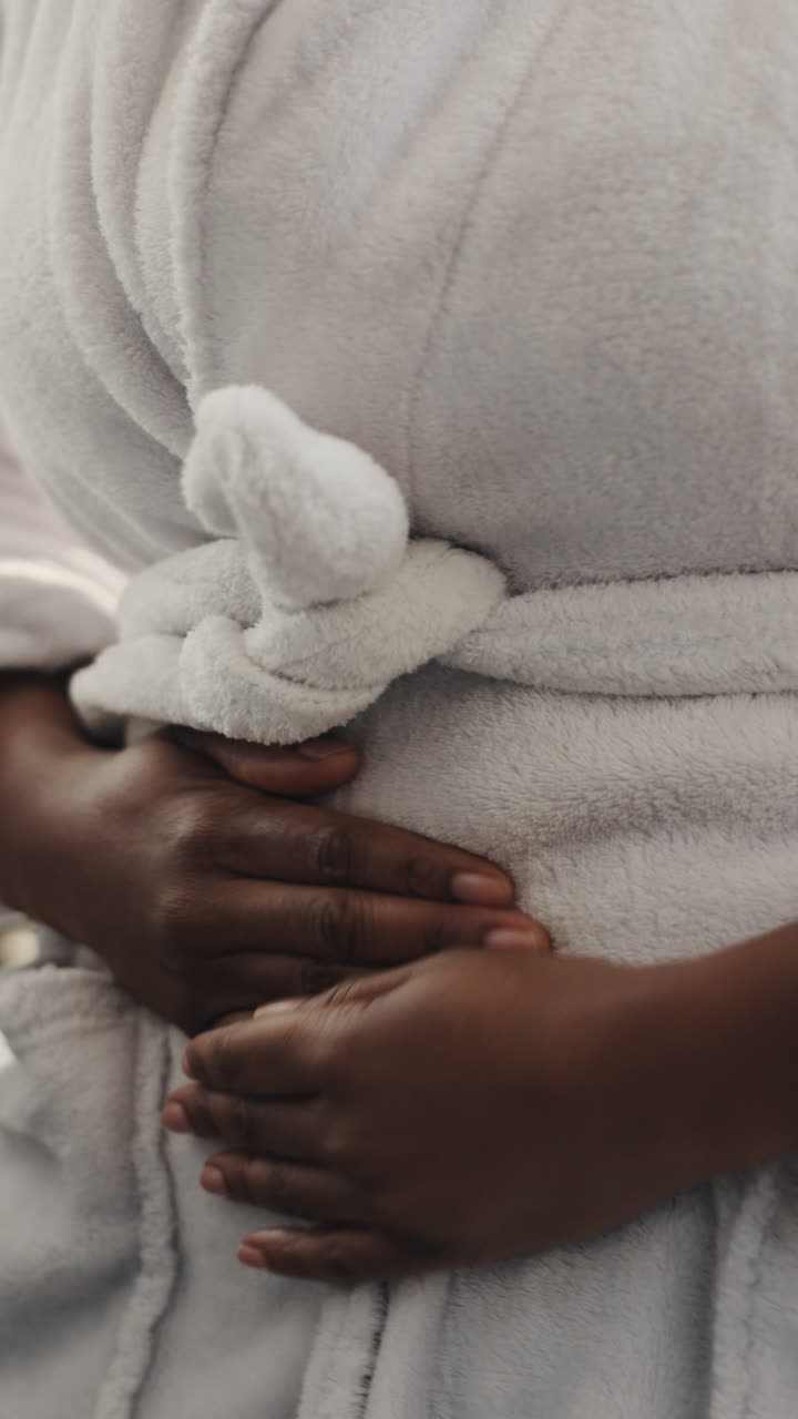 Close-up of Person Holding Stomach in White Bathrobe
