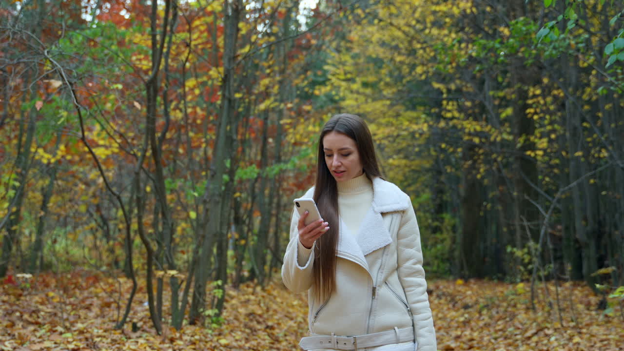 Kvinne bruker telefon i høstpark