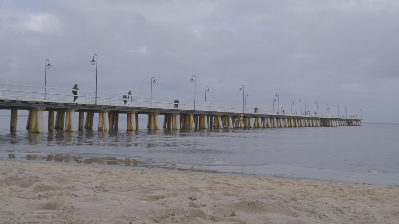 gente caminando en el muelle de orlowo en cámara lenta en un día nublado de invierno en el distrito costero de gdynia, polonia