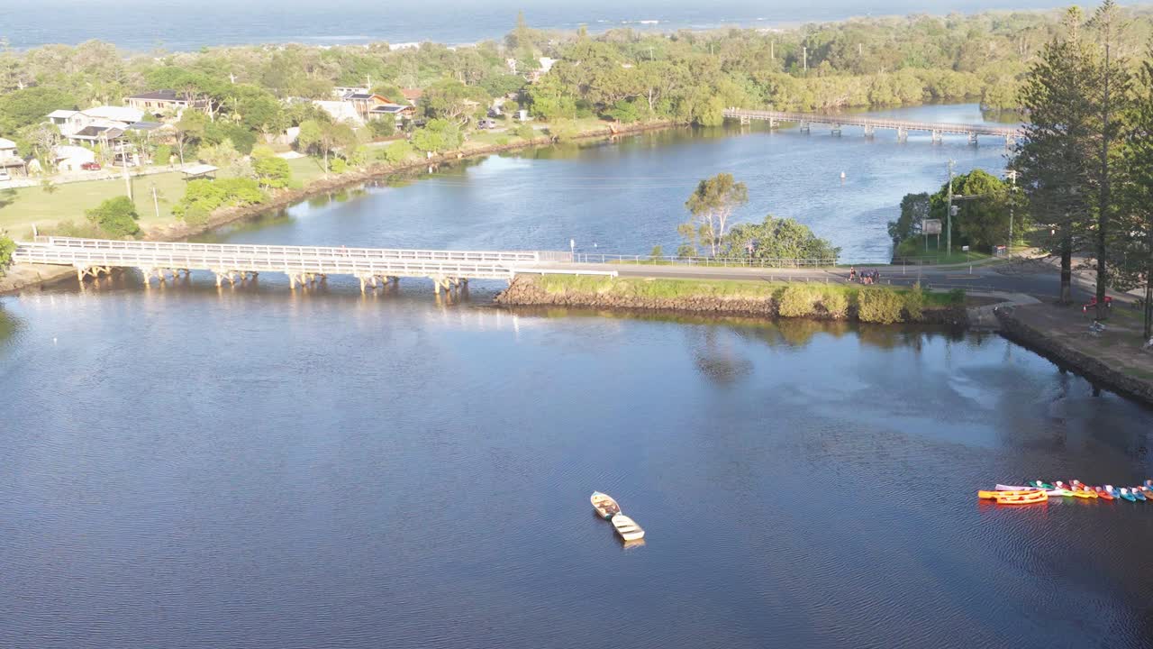 Aerial footage captures boats moving along the Brunswick River under bright daylight, showcasing serene natural surroundings and calm waters