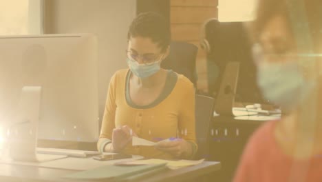 Spots-of-light-against-african-american-woman-working-at-office