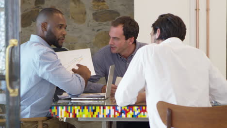 three men working together at computer in boardroom