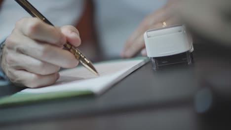 doctor signing and stamping prescription recipe, clinic physician hand writing diagnosis document with pen and paper on desk, close-up