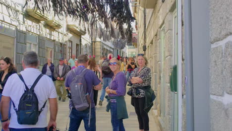 people walking on a narrow, historic street with decorations hanging from above