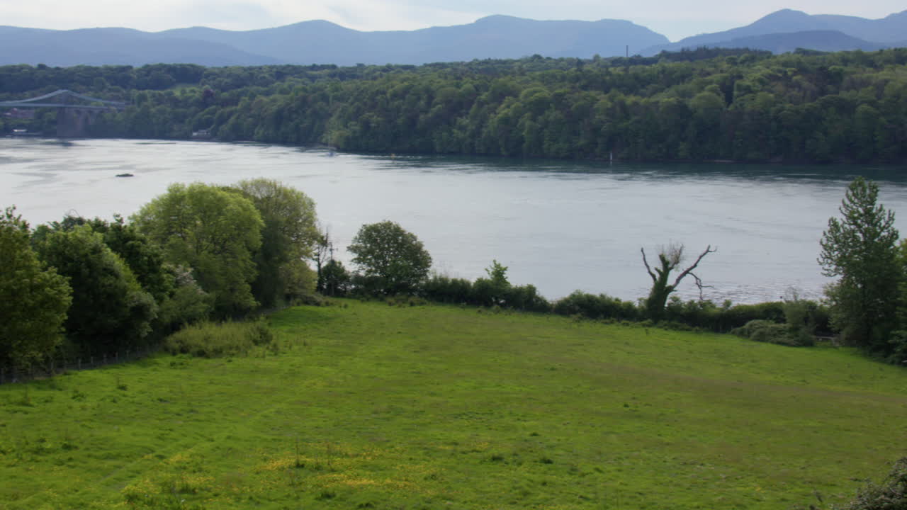 Extra wide panning shot of the Menai Strait with Menai Suspension Bridge in background at Llanfairpwllgwyngyll