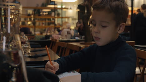 Niño-Dibujando-Cuando-Está-Sentado-En-El-Café